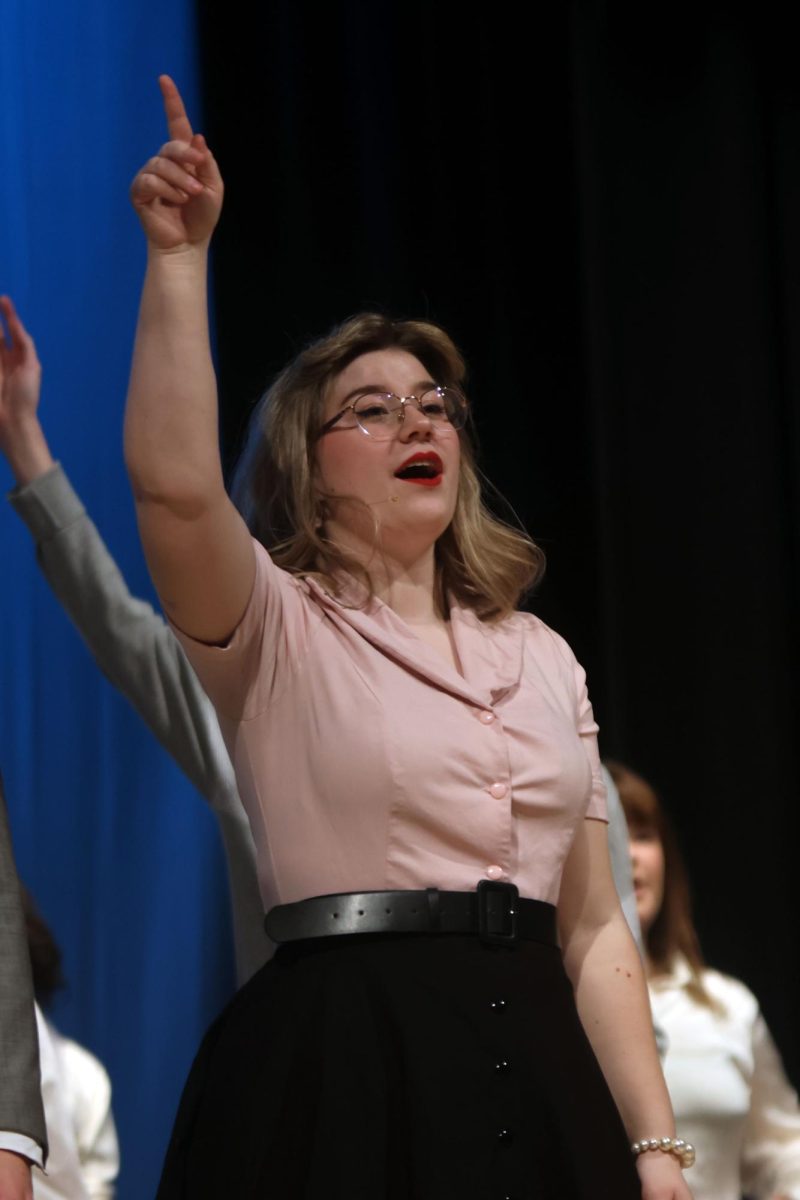 Singing along to “Bye Bye Birdie” during curtain call, Mrs. McAfee, played by senior Harley Quinn Boehm, points upward.