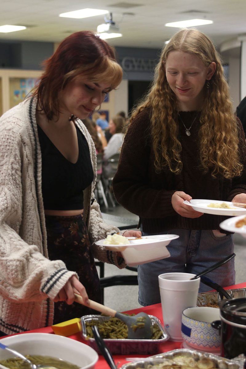 Filling their plates, seniors Ryleigh McCall and Sarah Reynolds get food at clubsgiving dinner.