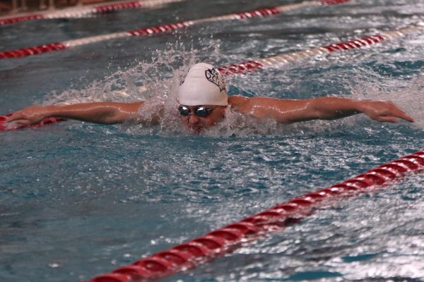 Coming up for a breath, sophomore Gavin Hurt competes in the butterfly.