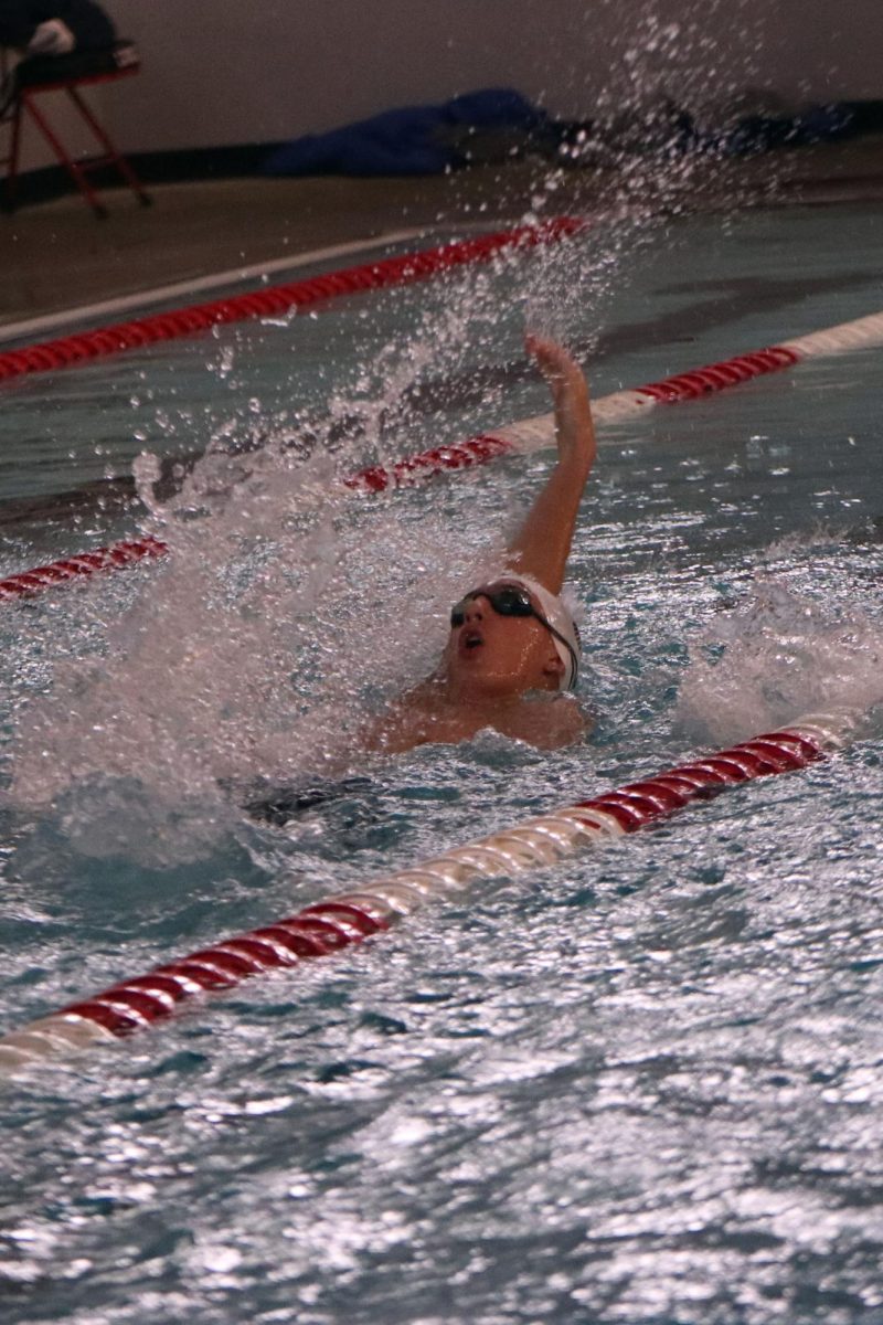 With his arm back, freshman Turner Bruce competes in the backstroke.