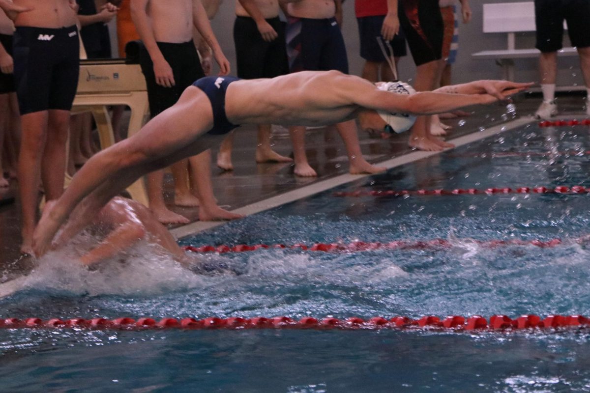 Arms stretched in front of him, junior Evan Wendler dives into the pool during the relay.