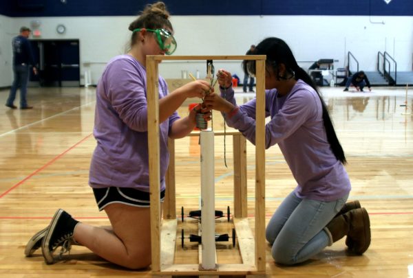 Juniors Hannah Lewis and Alivia Thatlor rig the weight that will propel their machine in the Scrambler event.