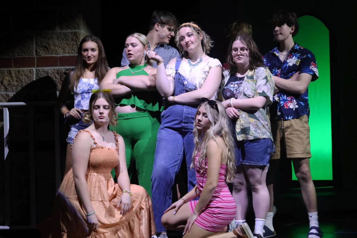 Lead by Donna, played by senior Riley Martin, the cast of Mama Mia pose in the conner of the stage during “Honey Honey”