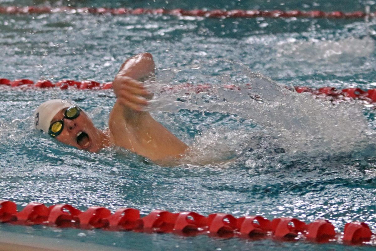 Arm moving up, freshman Declan Coleman takes a breath while swimming freestyle. 