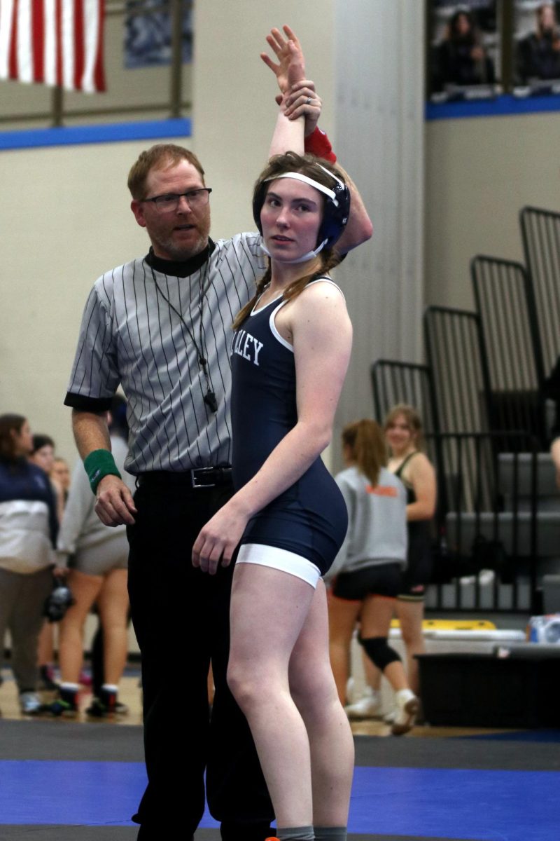 After winning her match, junior Piper Wendler looks into the stands with her hand raised in the air.