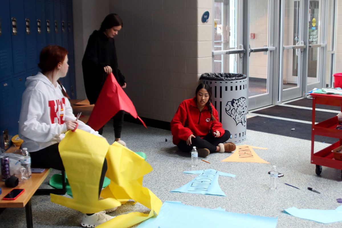 Freshmen Hadley Doyle, Ellie Newell, and Lyci Manirad craft arrow-shaped signs in fun colors.