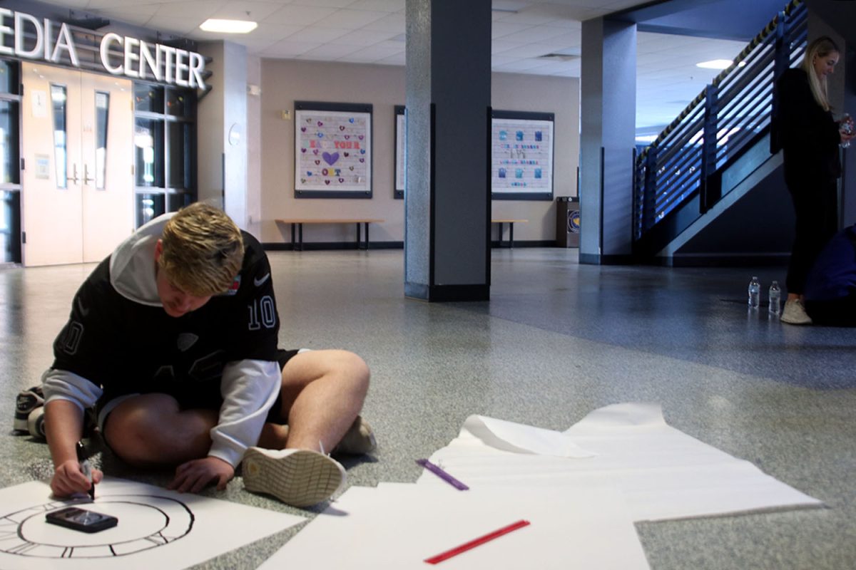 Senior Jack Fulcher draws a clock on a Back to the Future poster.