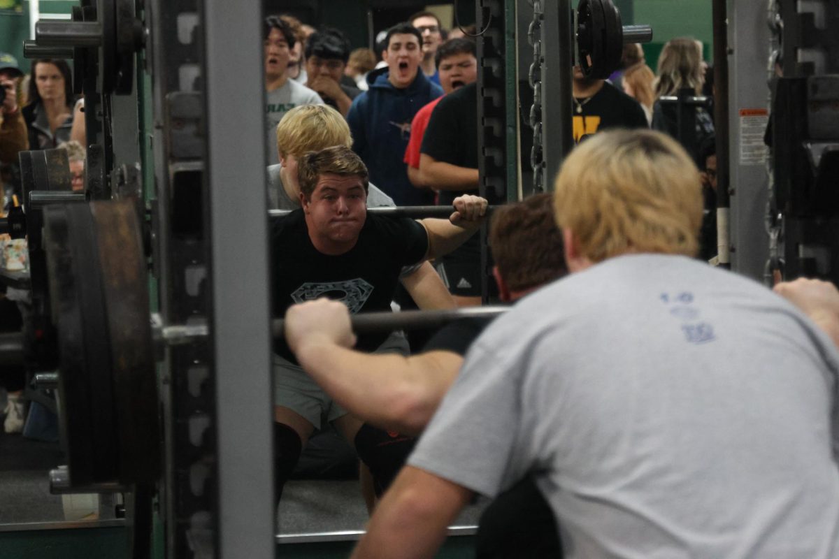 Attempting a new squat personal record, junior Hank Danielson gives his all while observers cheer him on. 