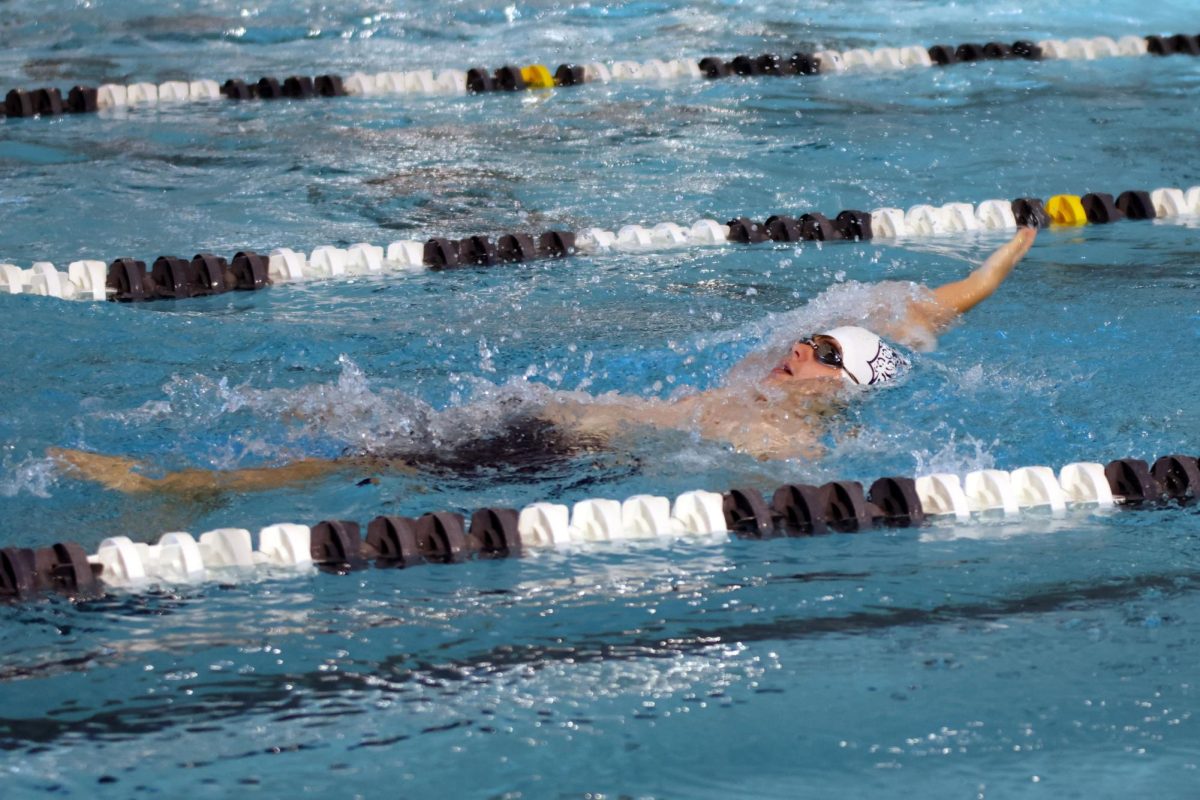 Reaching his arm back, freshman Owen Vielhauer swims backstroke.