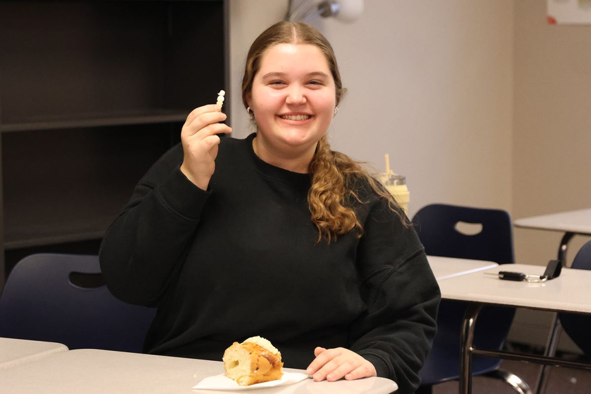 Holding the plastic doll in her fingertips, senior Kate Haney celebrates finding the token which means she will have good luck for the year.