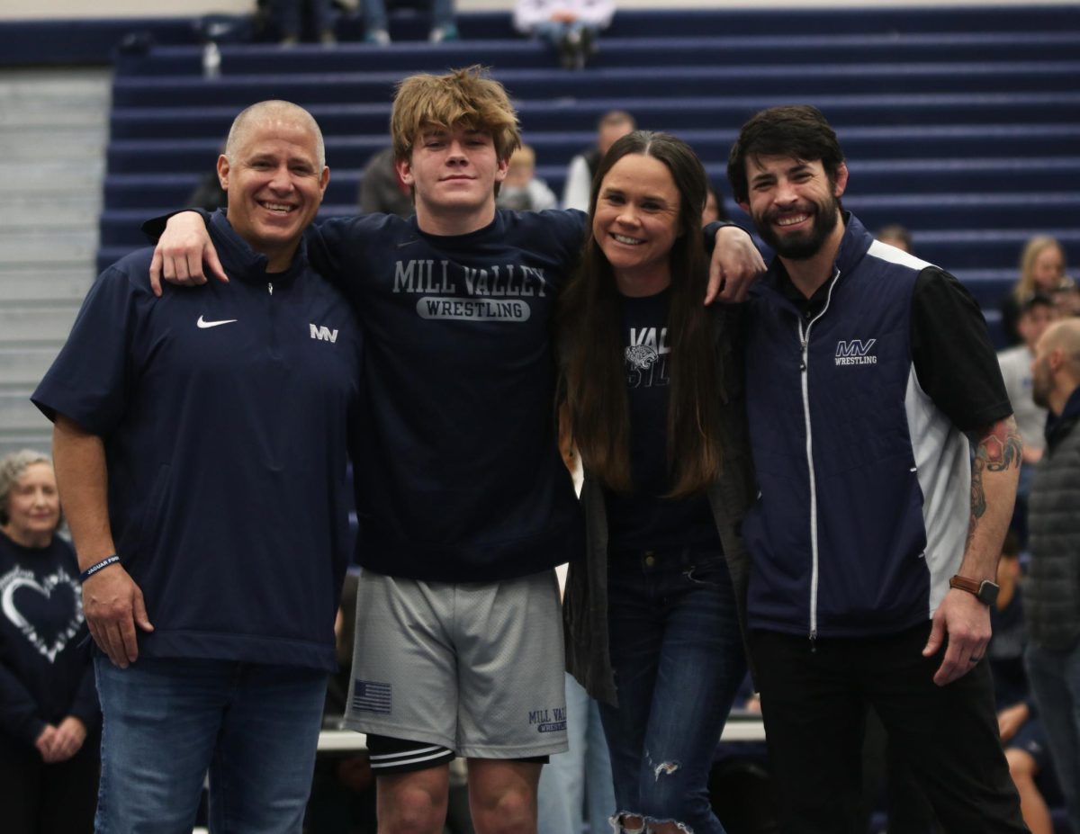Posing for the camera, senior Haden Applebee stands in front of the camera with his family and head coach Joseph Lazor.