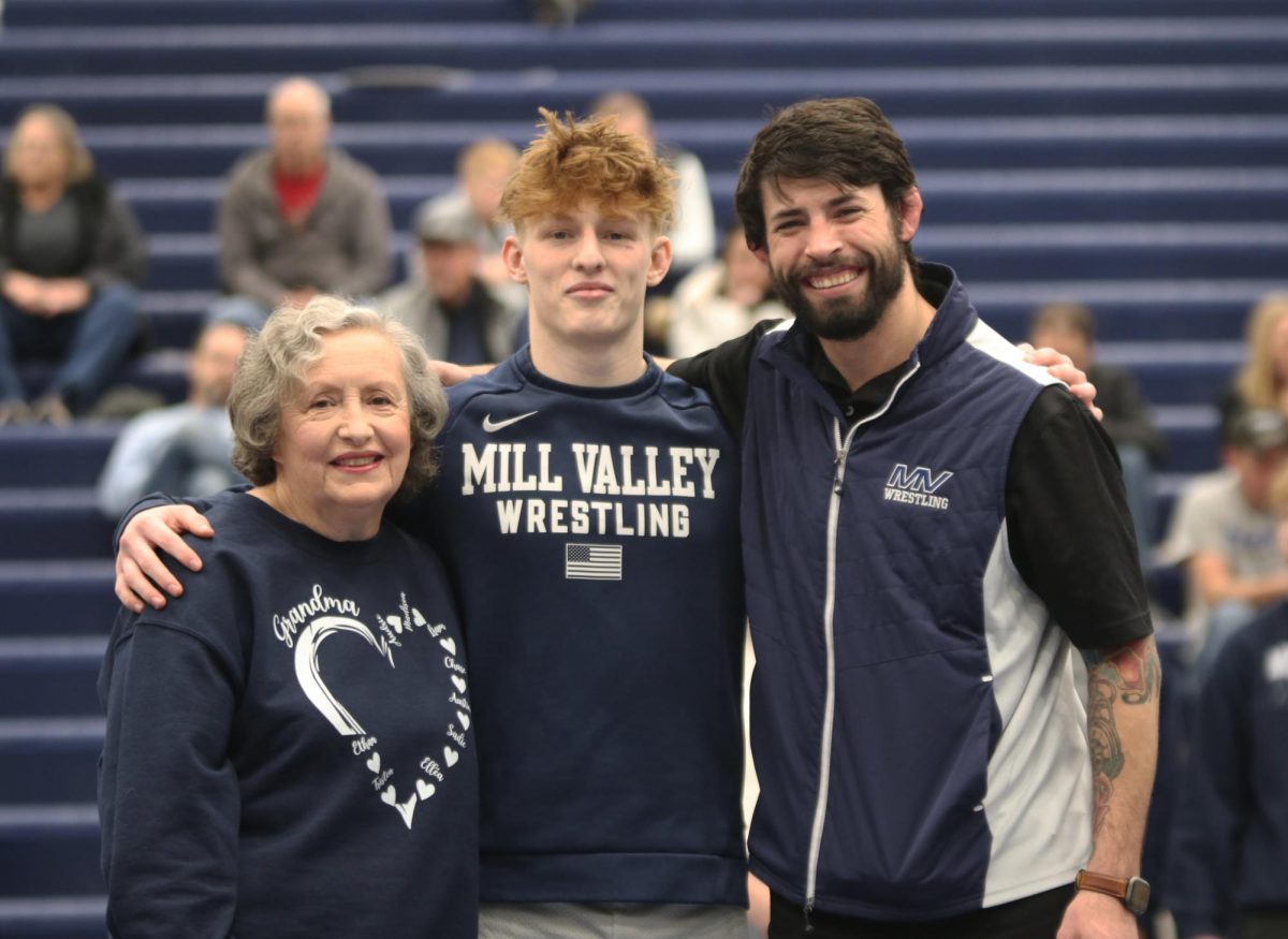 Posing for the camera, senior Austin Cline stands in front of the camera with his family and head coach Joseph Lazor.