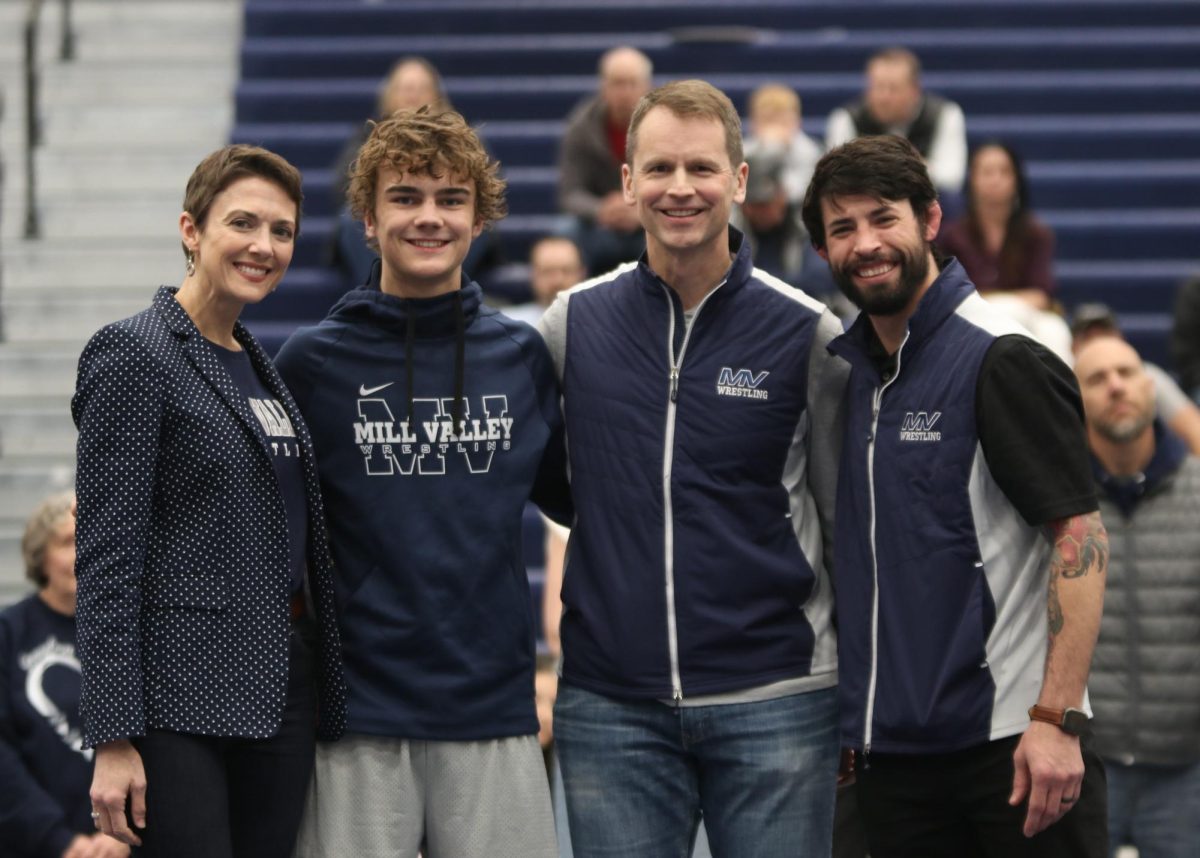 Posing for the camera, senior Brady Mason stands in front of the camera with his family and head coach Joseph Lazor.