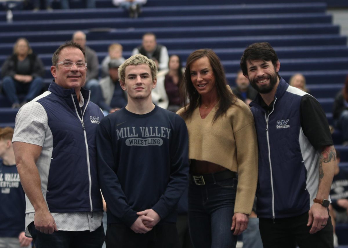 Posing for the camera, senior Maddox Casella stands in front of the camera with his family and head coach Joseph Lazor.