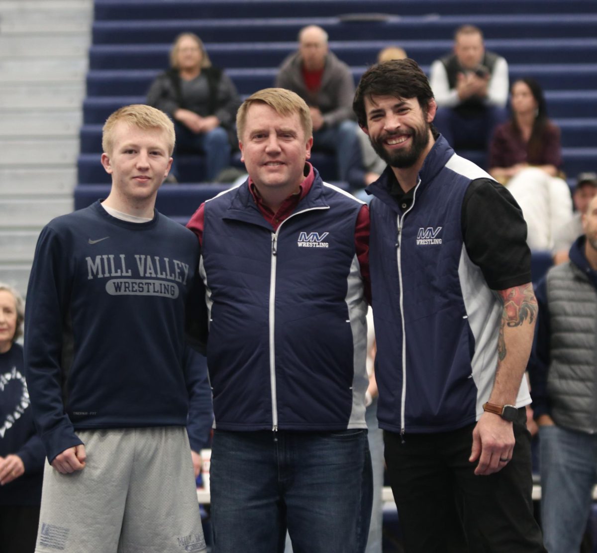 Posing for the camera, senior Robert Hickman stands in front of the camera with his family and head coach Joseph Lazor.