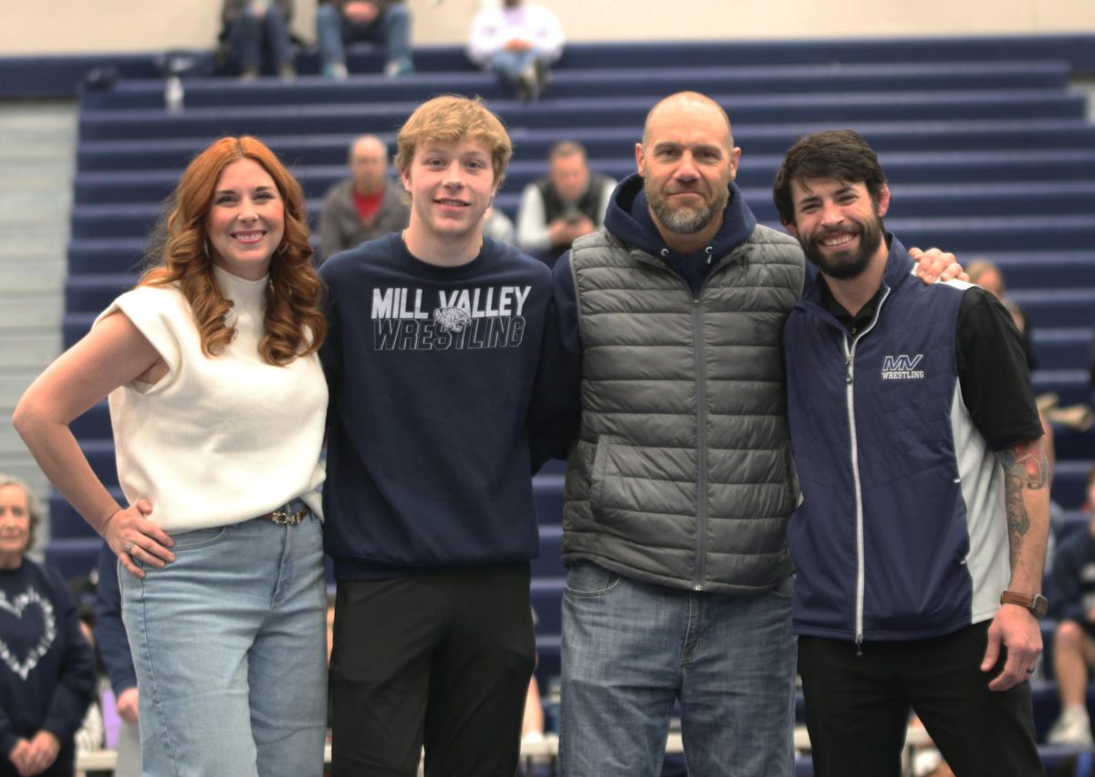 Posing for the camera, senior Colton Clark stands in front of the camera with his family and head coach Joseph Lazor.