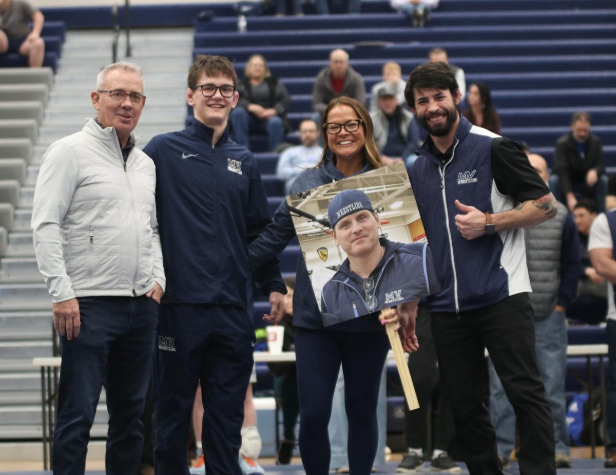 Posing for the camera, senior Dillon Cooper stands in front of the camera with his family and head coach Joseph Lazor.