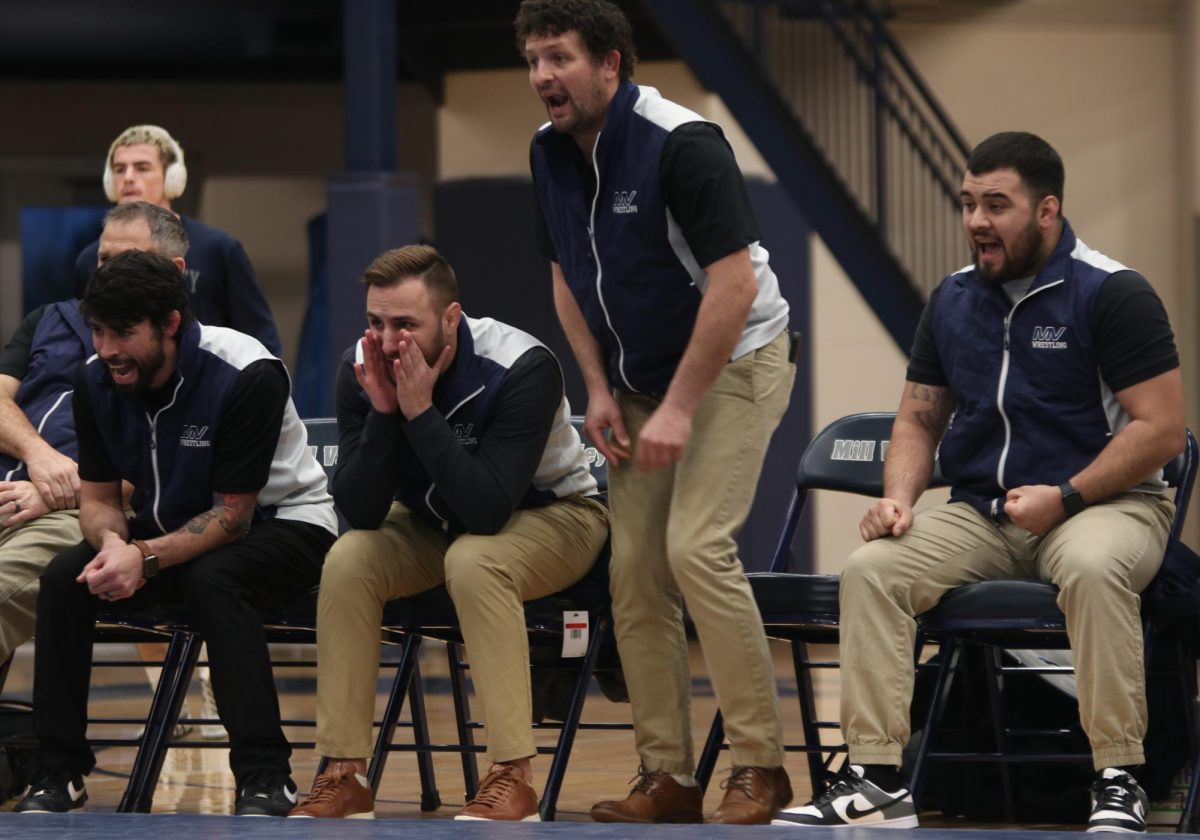 Cheering from the sidelines, head coach Joseph Lazor and assistant coaches Brayan Burnett, Jake Ellis and Julian Winters shout words of encouragement to sophomore Jeredy Nilges during his match.