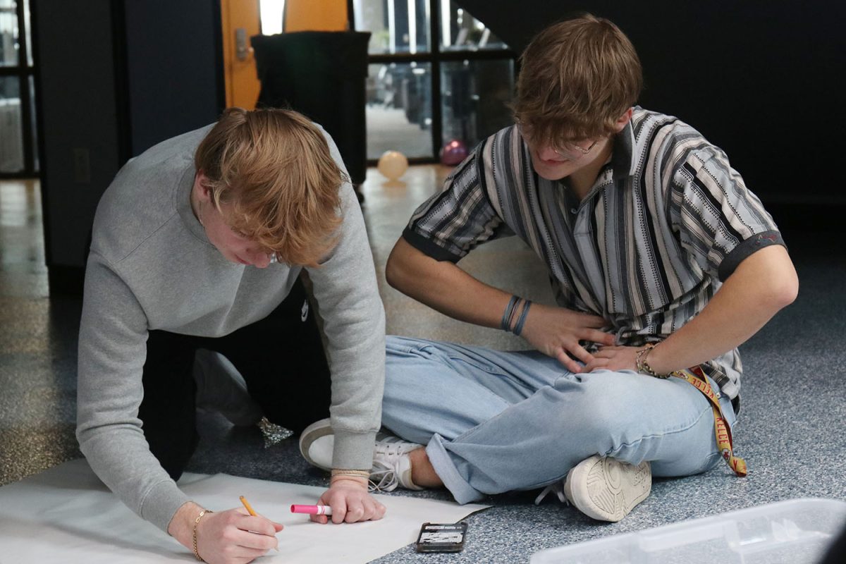 Using teamwork, junior Logan Koester and senior Blake Powers map out their poster together.
