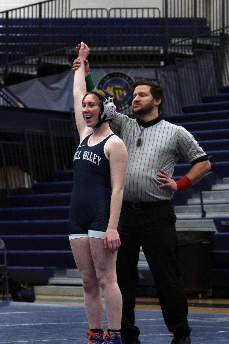Smiling, junior Piper Wendler raises her hand in victory after her match. 
