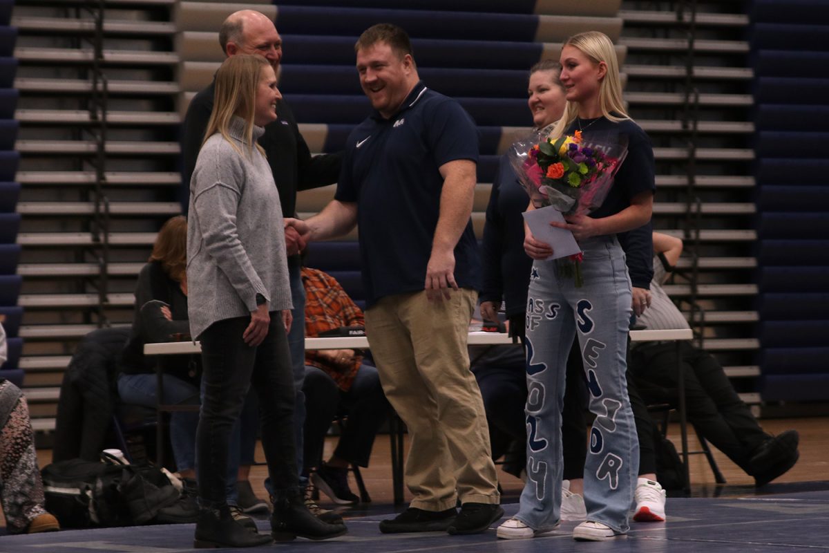 Flowers in hand, senior Emily Summa stands with her family and coaches on senior night.