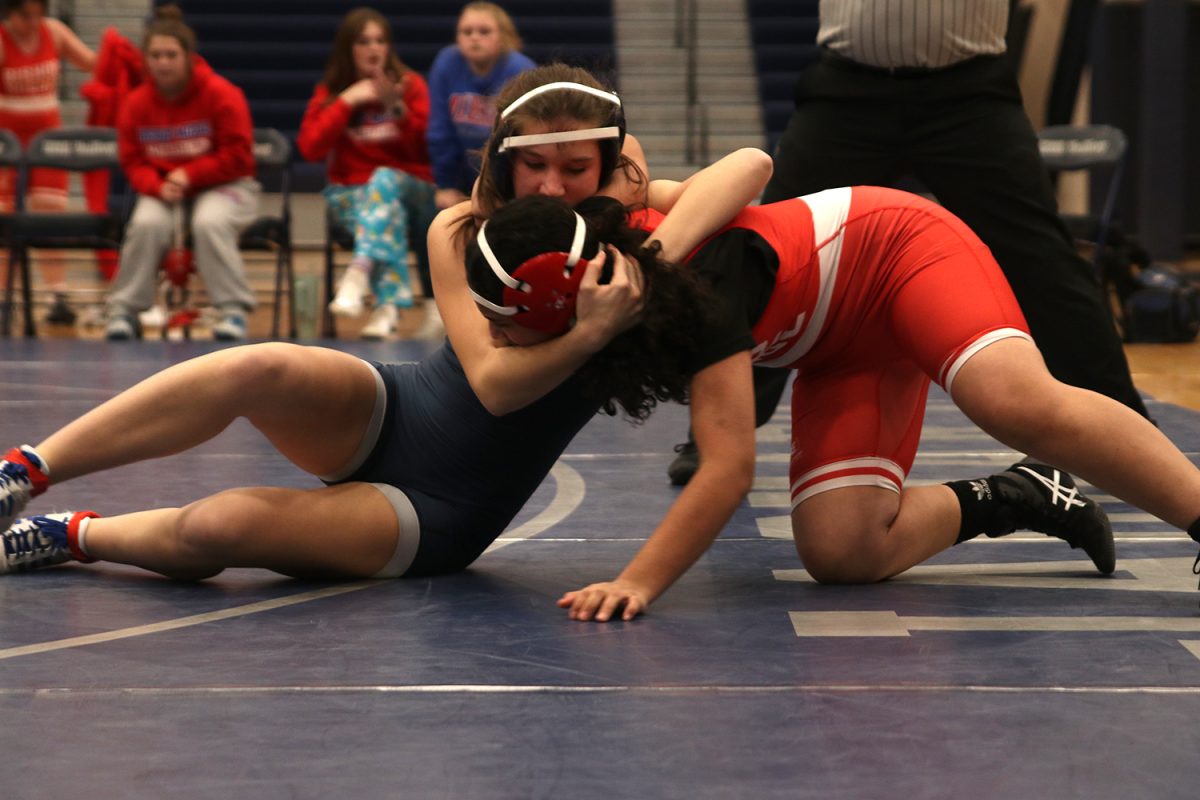 Taking her opponent down, junior Jule Kohorst participates in a home wrestling match.