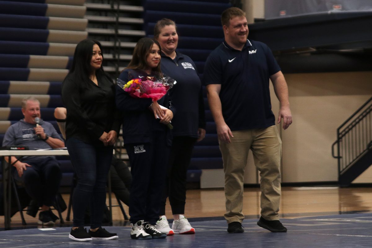 Ready for a picture, senior Nathalie Gutierrez smiles with her mom and coaches.