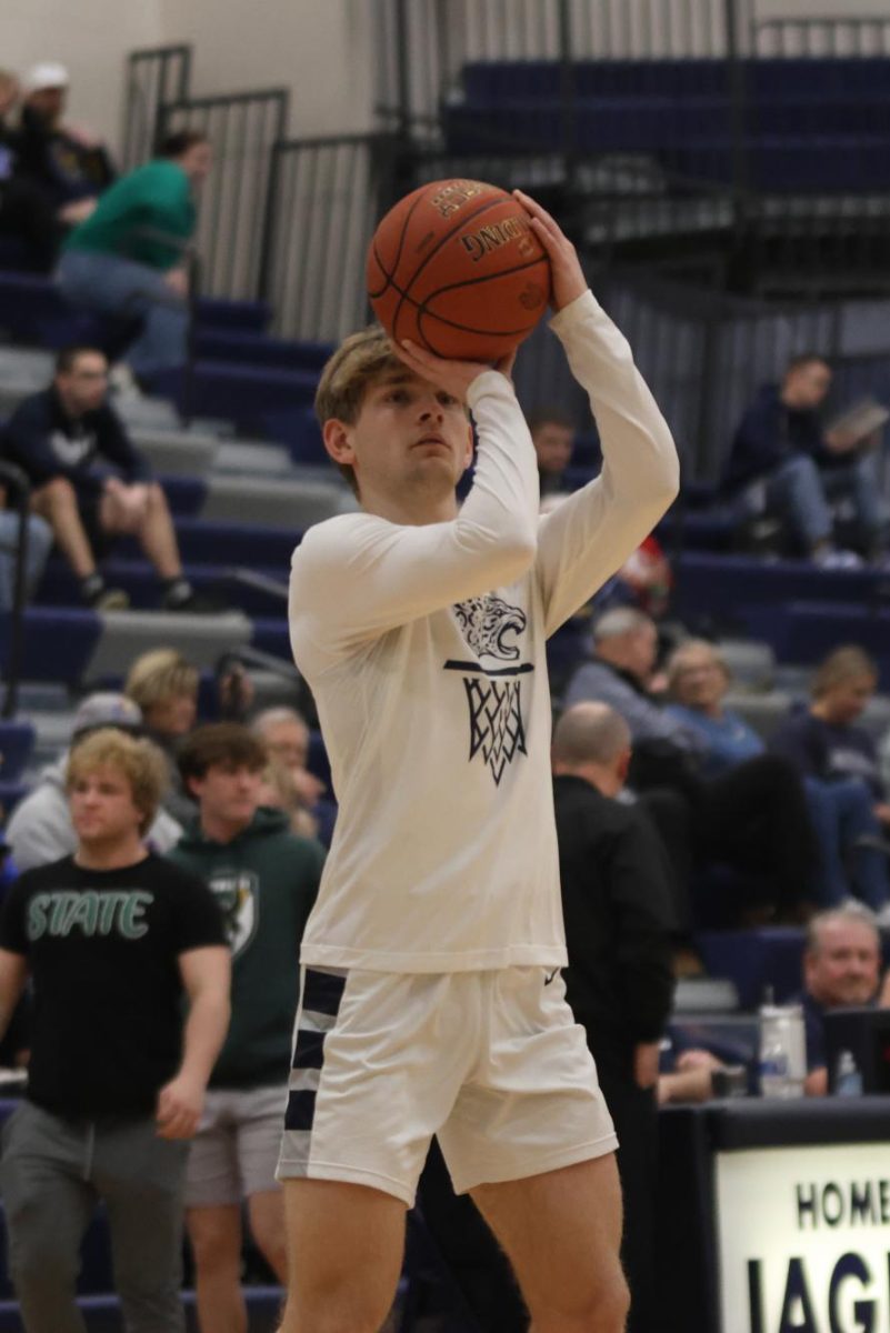 Senior Bryant Wiltse shoots three pointers while warming up before the game.