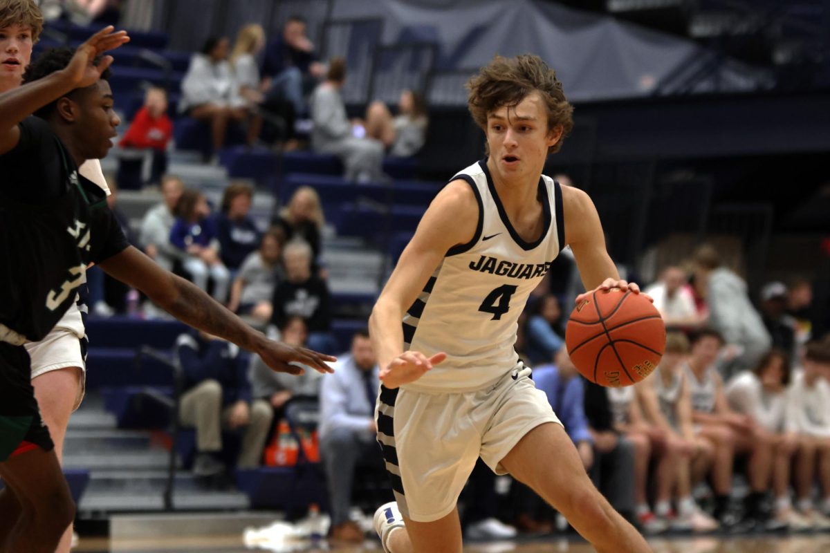 Sophomore Reece Riedel sticks out his arm and dribbles around his opponent.