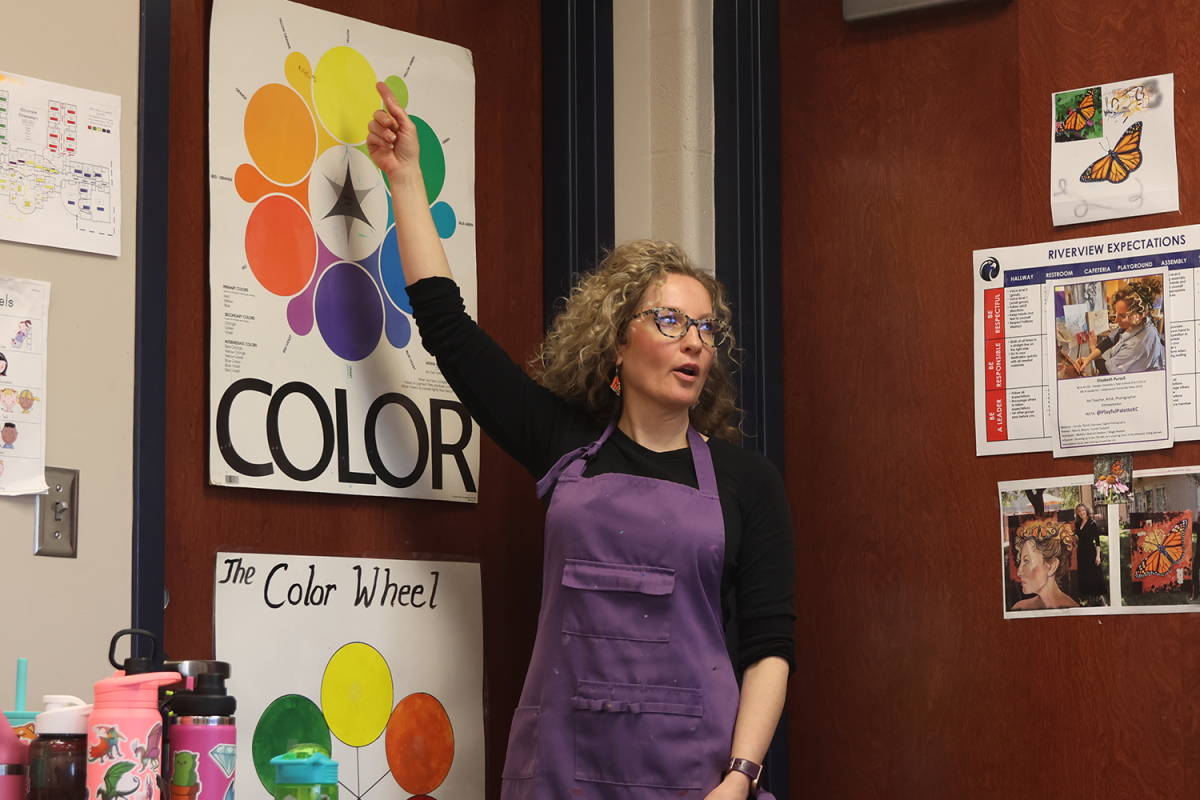 Pointing up, Riverview art teacher Elizabeth Pursell explains the color wheel as her class prepares to paint their clay projects.