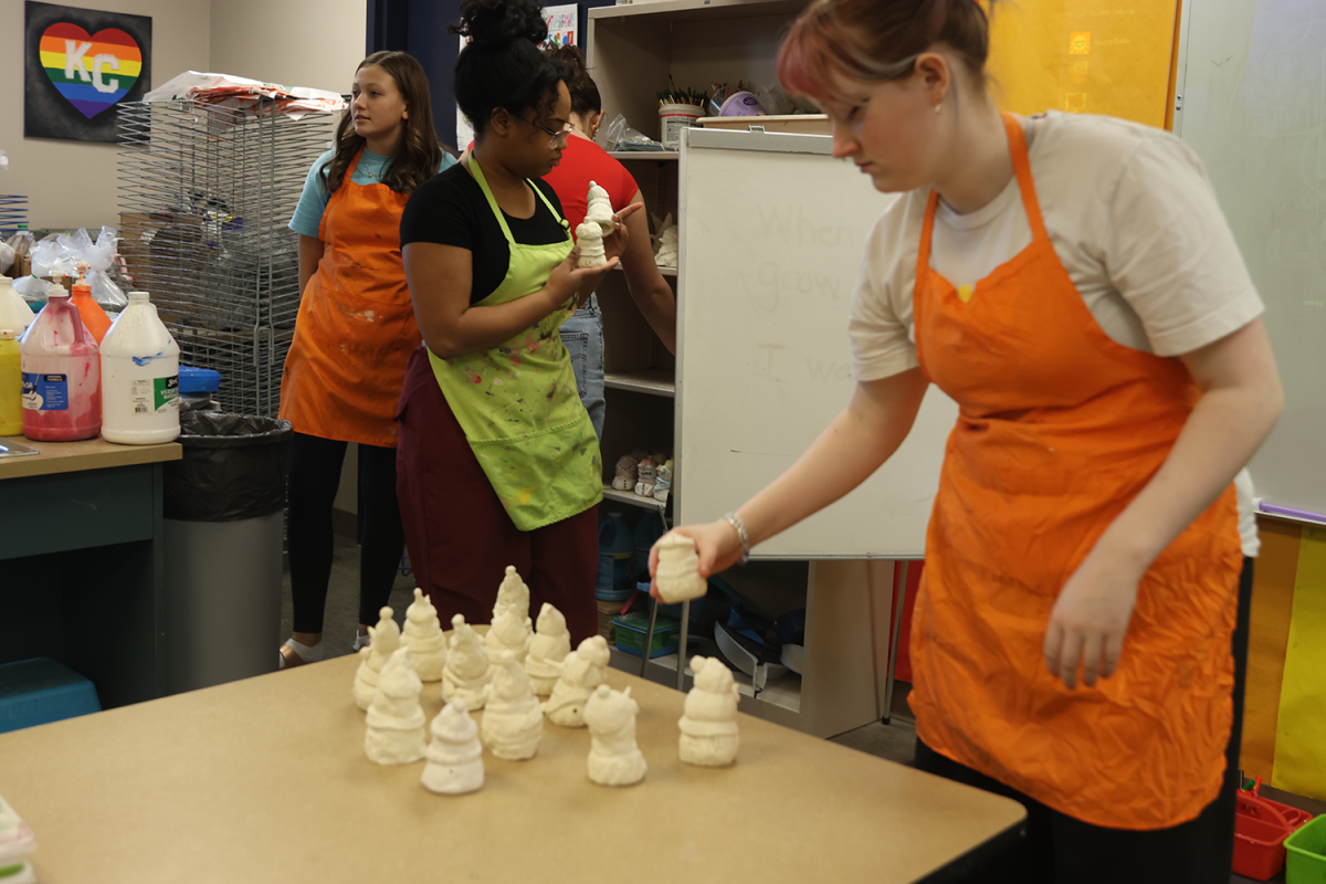 Senior Emma Clement, junior Autumn Graves, and Desoto freshman Taryn Round help pass out students clay projects. 