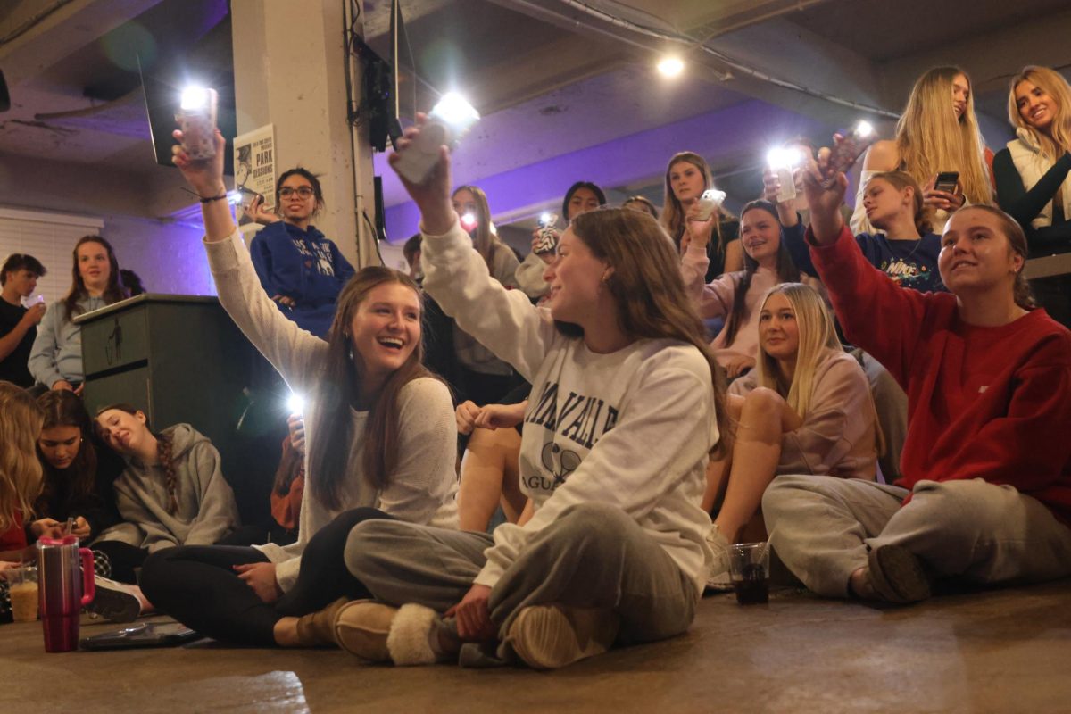 Leading the crowd, seniors Lucy Roy and Ellie Walker waive their flashlights in the air.