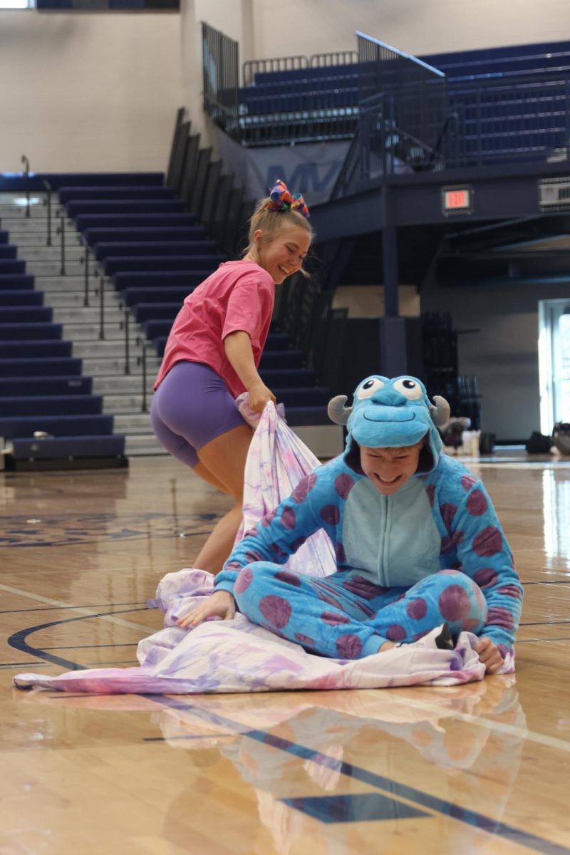 Tugging the blanket, winter homecoming queen candidate senior Jaiden Fisher attempts to pull winter homecoming king candidate senior Garrett Cronin to the other end of the gym.