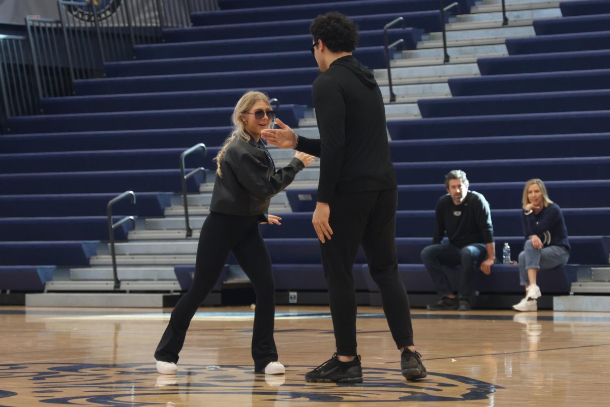 Hands out, winter homecoming candidates seniors Violet Hentges and Truman Griffith show their handshake to the crowd.