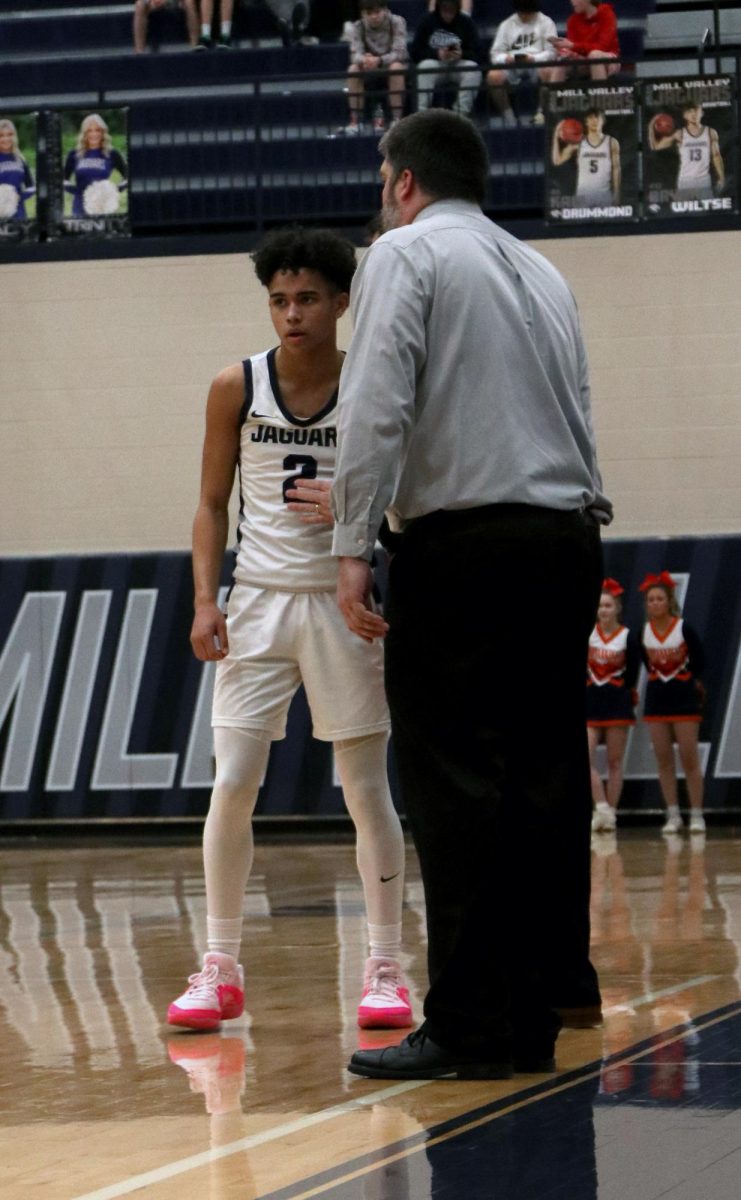 In between plays, sophomore JaKhai Carter talks to head basketball coach Kurt Bangle. 