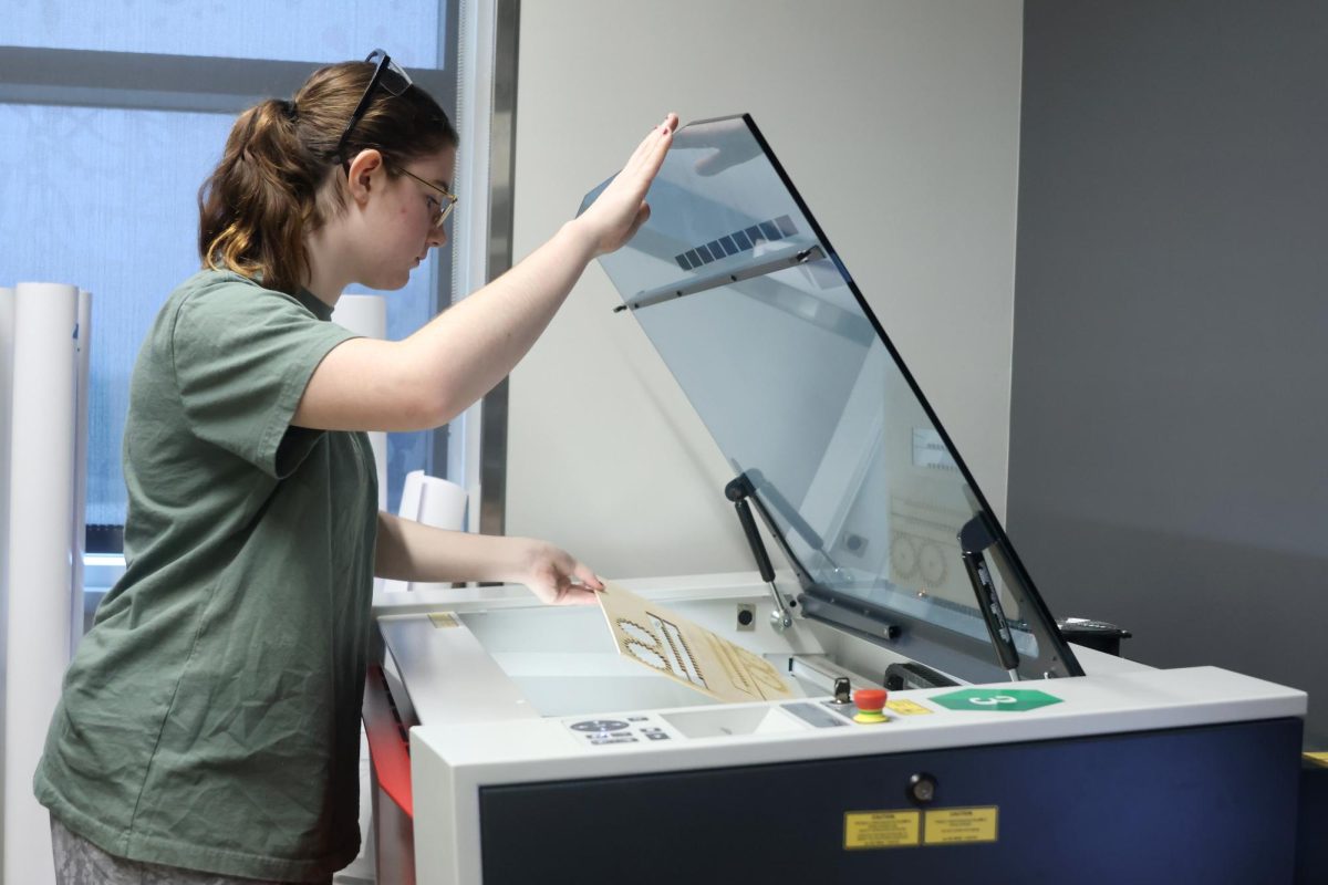 Removing the pieces from the laser cutter, junior Lexus Pennel cuts out a set of wooden gears to use for their mechatronic Thursday, Jan. 25. “We are making a moving face of art that is fully functional with either a manual piece for movement or a small motor,” Pennel said. “The project helps us learn how to use more of our design and creation skills when it comes to approaching a new task.” 