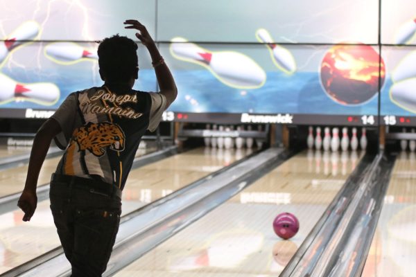 Stepping forward, freshman Joseph Wainaina bowls at the meet Tuesday, Jan. 30.