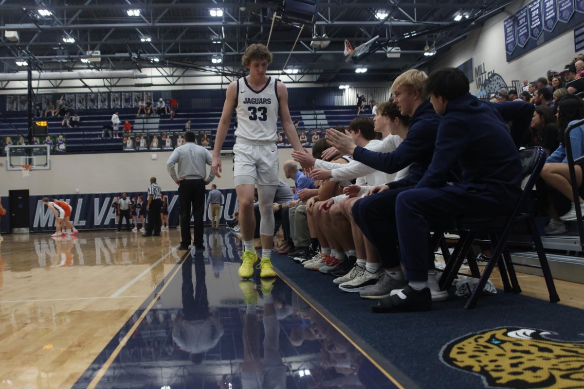 After coming off the court, senior Mason Kemp high-fives his teammates on the bench.