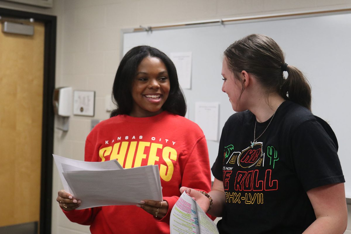 Looking at their papers, sophomores Tristyn Jones and Lillian Gibson laugh at a part of their script at forensics practice Wednesday, Feb. 22.

