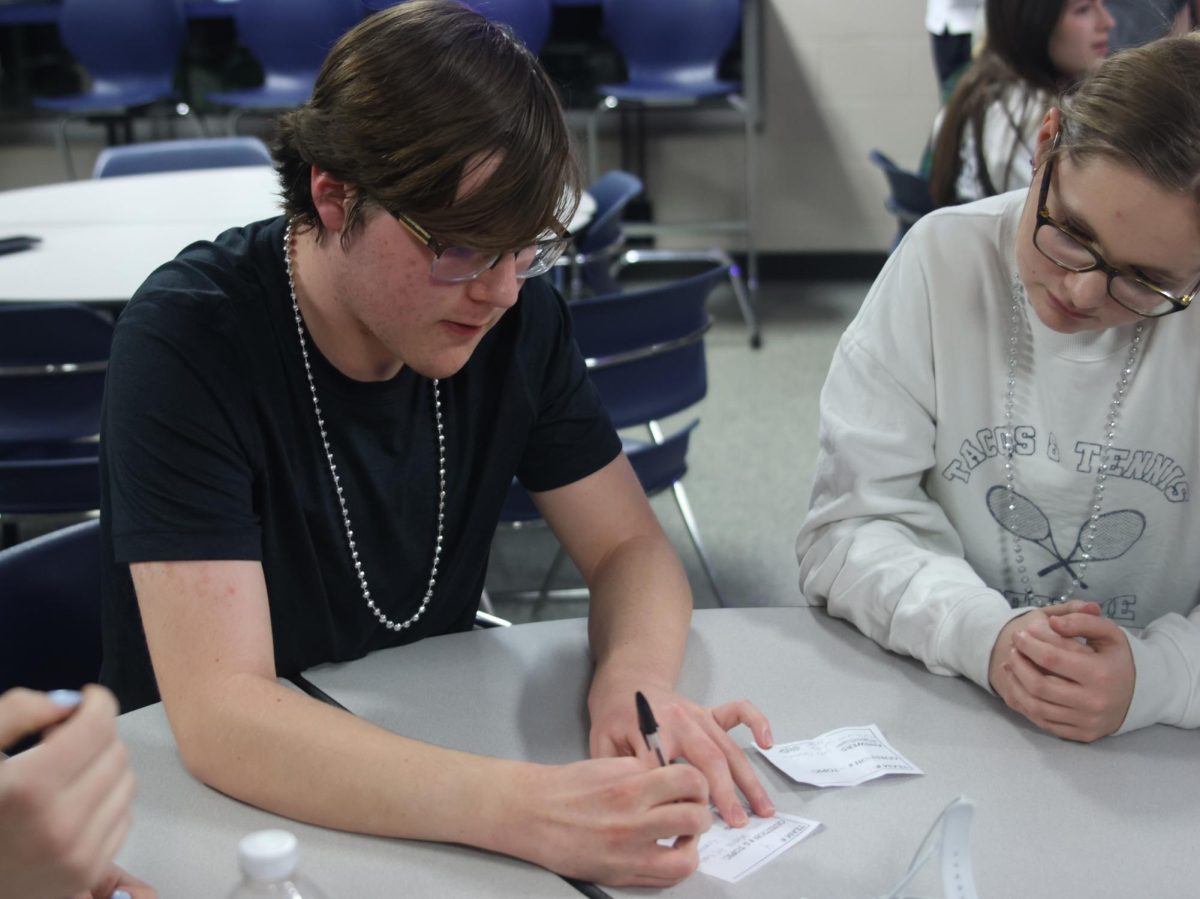 After discussing with their group, junior Marissa Akehurst watches sophomore Ian Weatherman writes down the possible answer to the question.