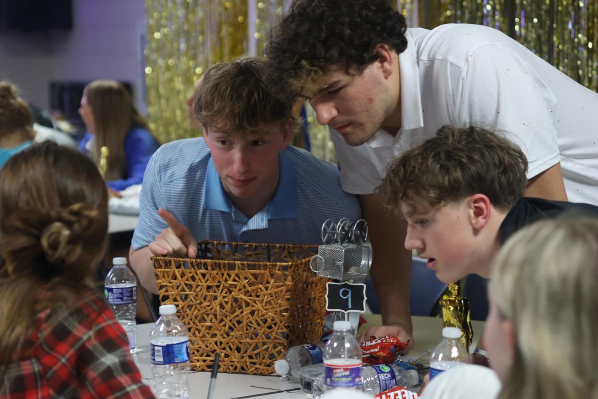 Discussing the answer, juniors Porter White, Abe Shaffer and Grayson Moore lean into the middle of the table so other teams won’t hear them.