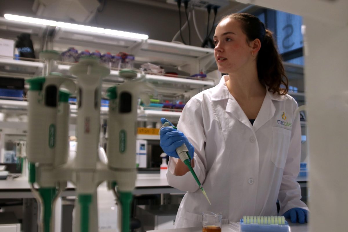 Looking to a classmate, senior Bridgit Duffin discusses her internship while pipetting water samples Friday, Jan. 26. 