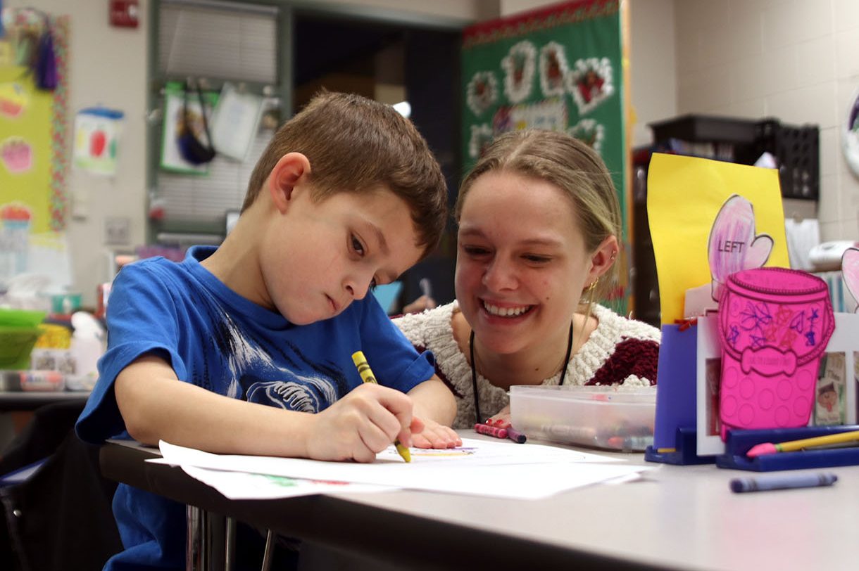 Interning, senior Kaylen Hyde helps kindergartener Greyson Rocco color his morning work Friday, Feb. 2.