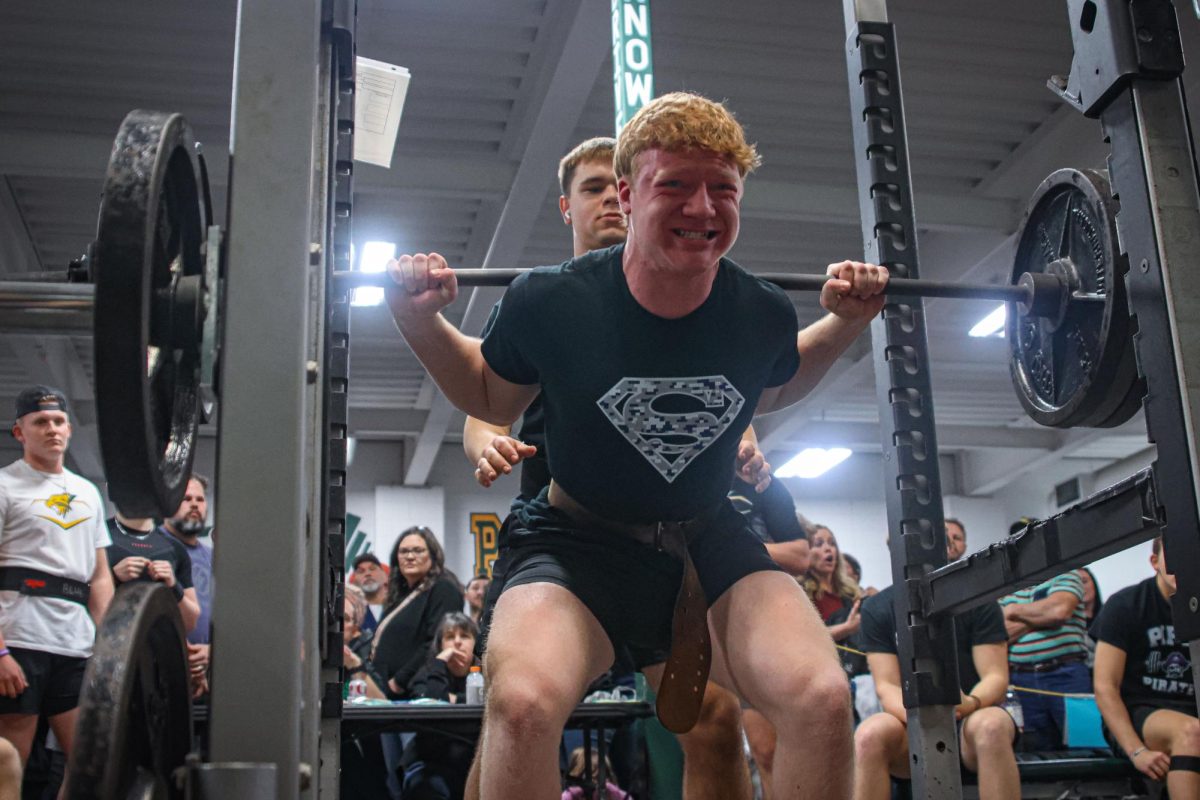 With the bar on his shoulders, junior Conner Wood grinds to lift the weight.