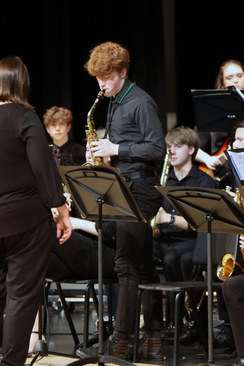 Standing up, junior Brayden Evans plays his solo on saxophone.