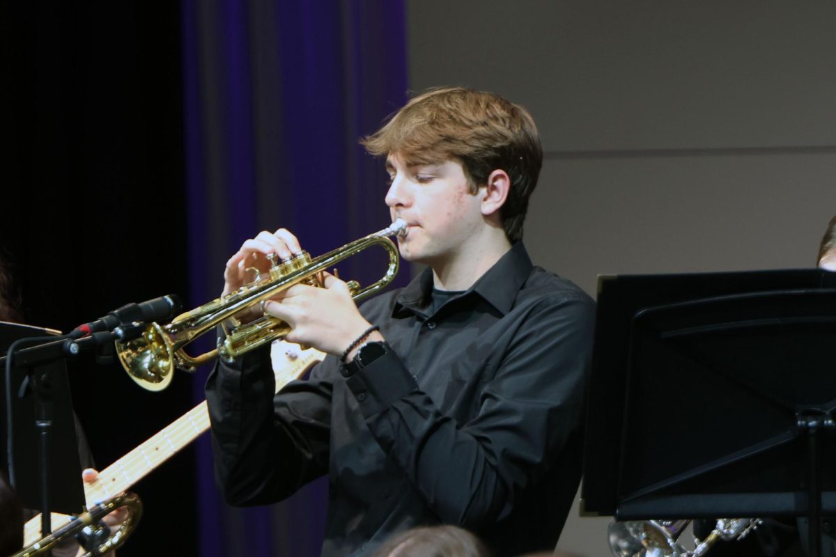 Looking at his music, junior Carson Reynolds plays the trumpet.