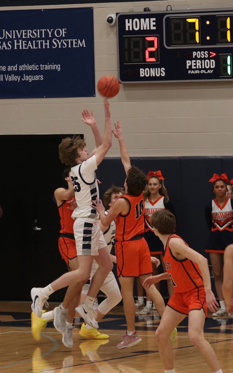 Going to score, junior Carter Kaifes blocks his opponent, jumping to make a basket.