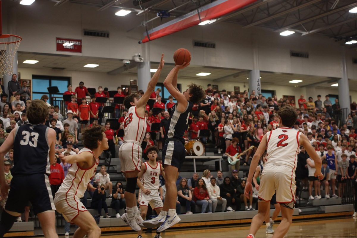 Going up for the jump shot, sophomore Reece Riedel attempts to avoid his opponents block during the playoff game.