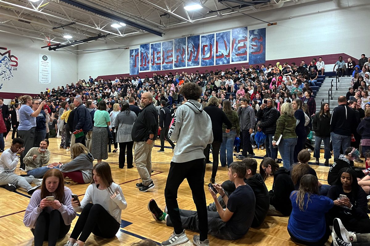 Sitting on the MTMS gym floor, groups of students talk with their friends while waiting for updates.