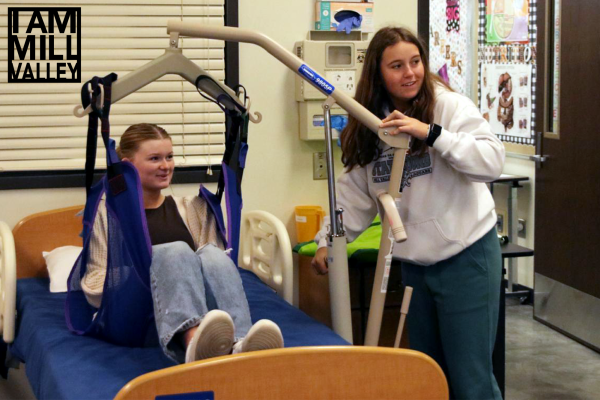 During her Health Careers class at EDTEC, senior Elly Vanrheen lifts senior Jenna Graber from a patient care bed to practice moving patients Wednesday, April 5, 2023. This class was one of the first steps in VanRheen’s journey to becoming a CNA.